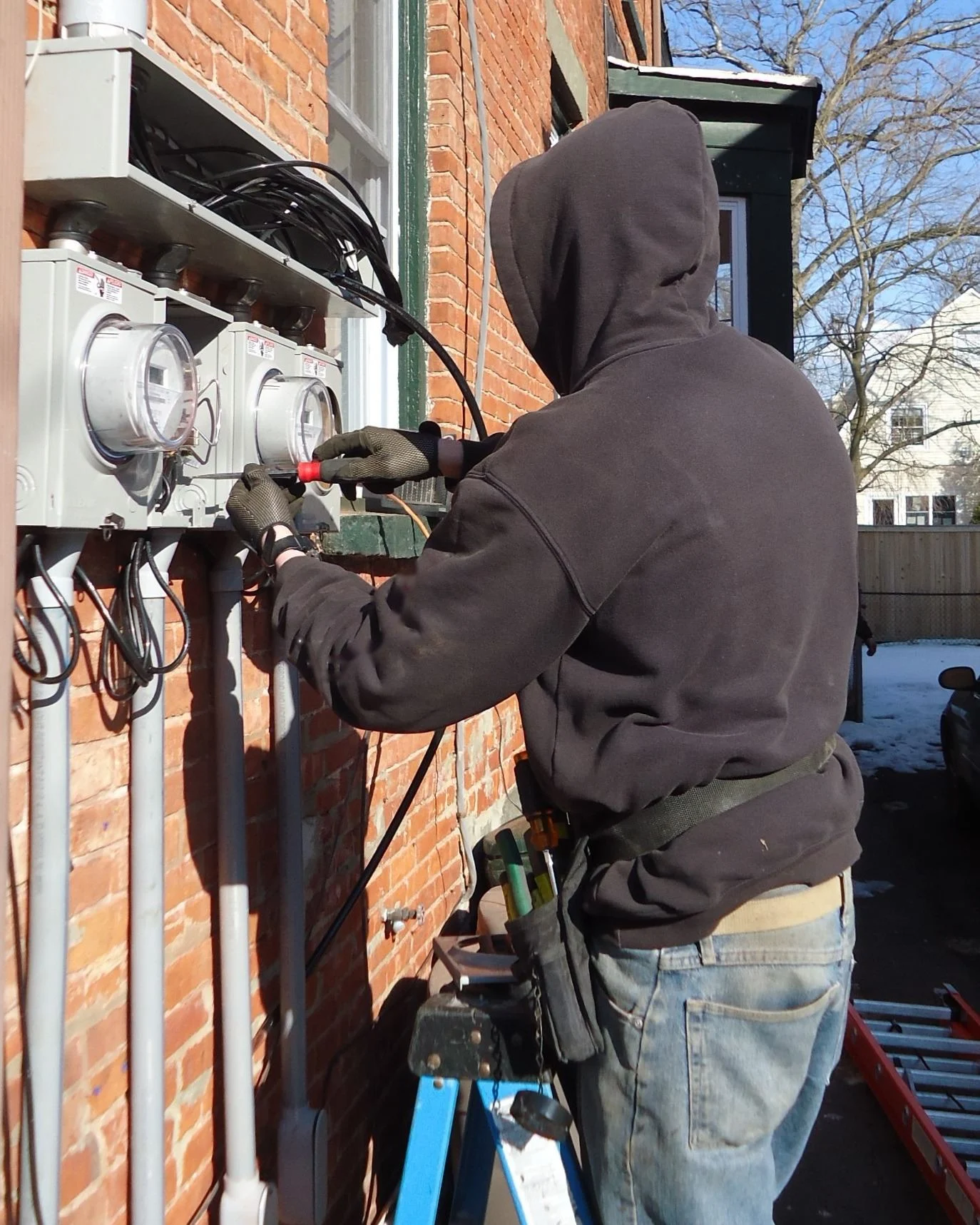 Kestrel Line electrician wiring a meter panel on a brick home